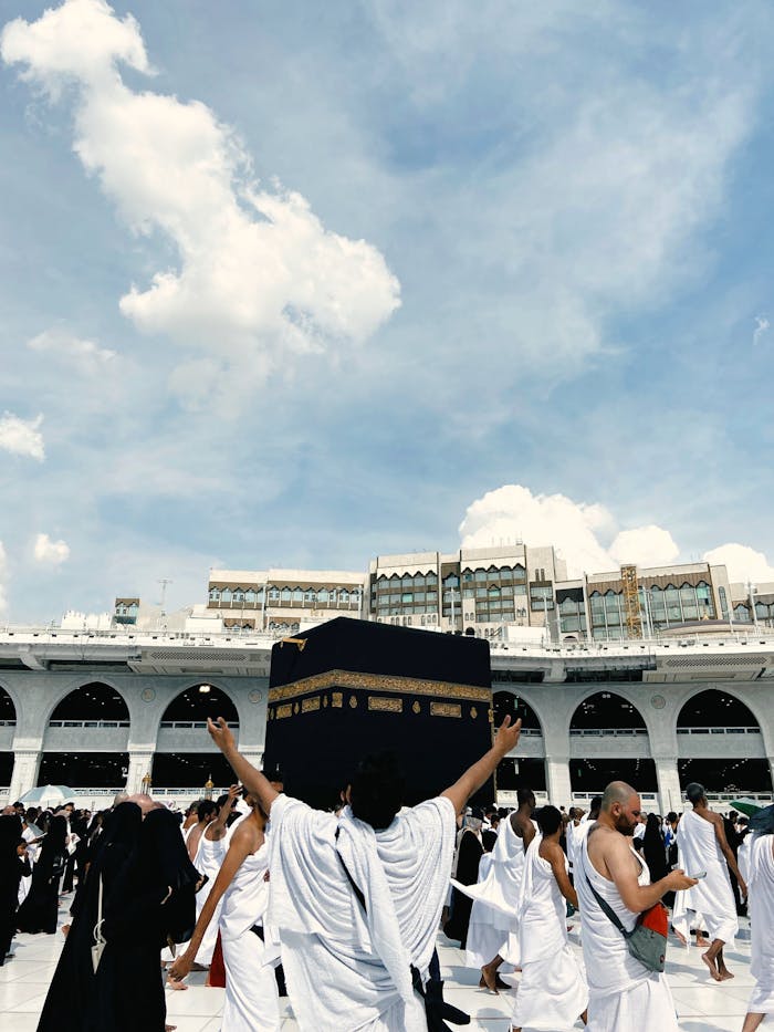 embark A large crowd of pilgrims performing Hajj at the Kaaba, showcasing religious devotion and unity.